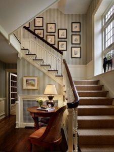 Escalera decorada con friso lacado en blanco, moqueta de sisal y colección de fotografías